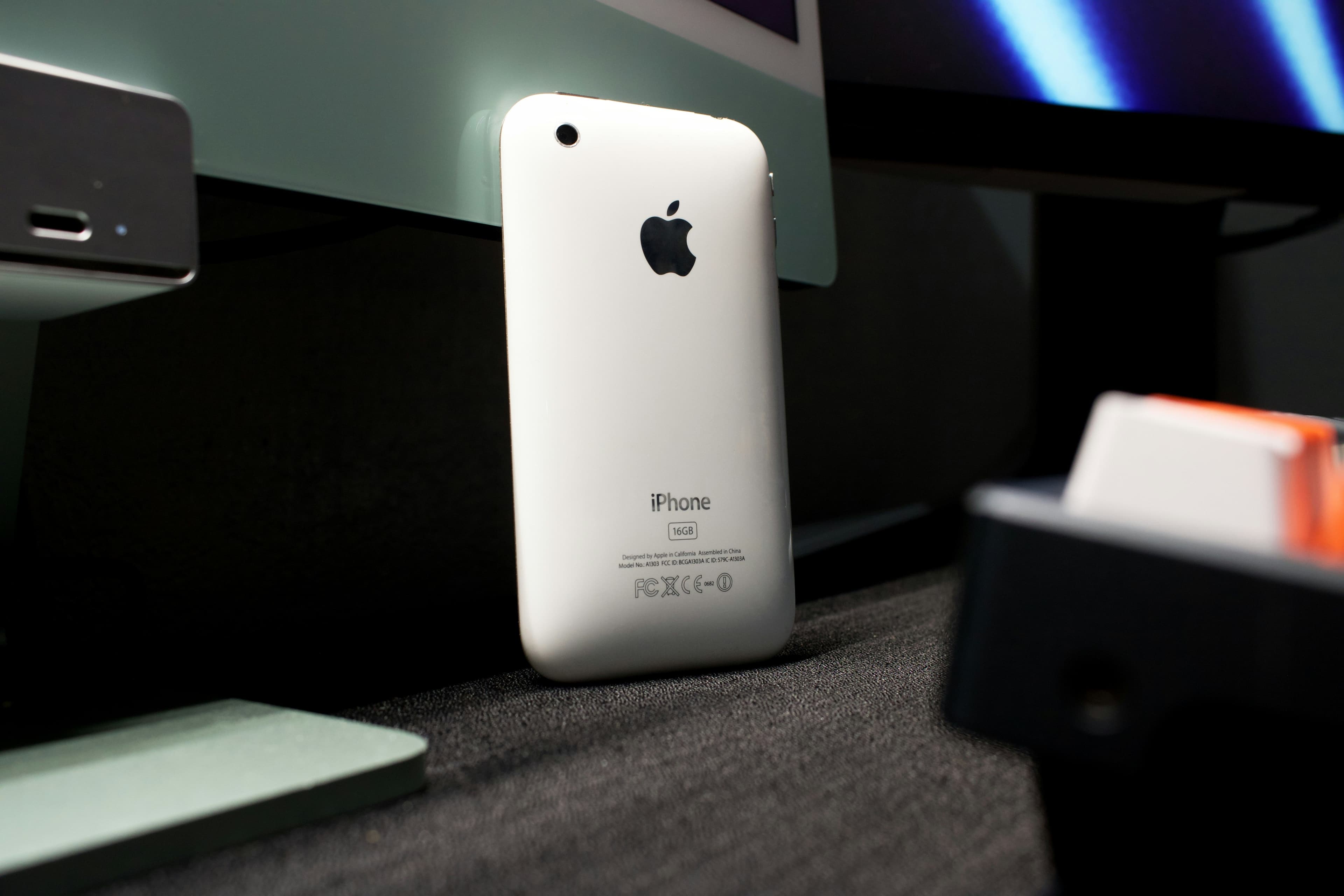 A white iphone sitting on top of a desk next to a monitor